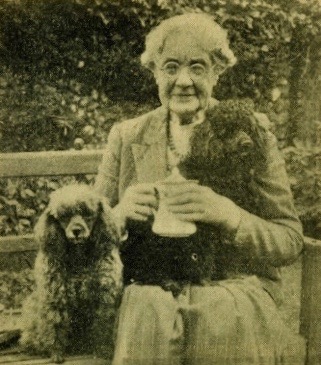Louise Hoare photographed for her 80th birthday accompanied by her French poodles Andre (lap) and Perita (bench).